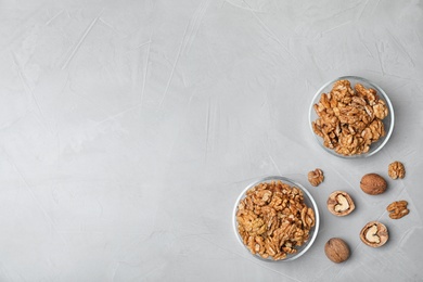 Dishware with walnuts on grey background, flat lay. Space for text