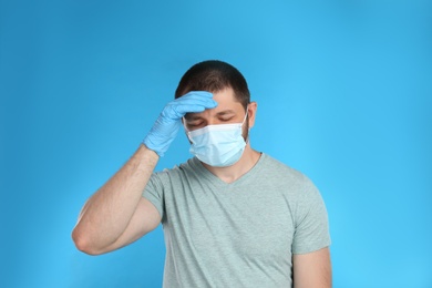 Photo of Stressed man in protective mask on light blue background. Mental health problems during COVID-19 pandemic