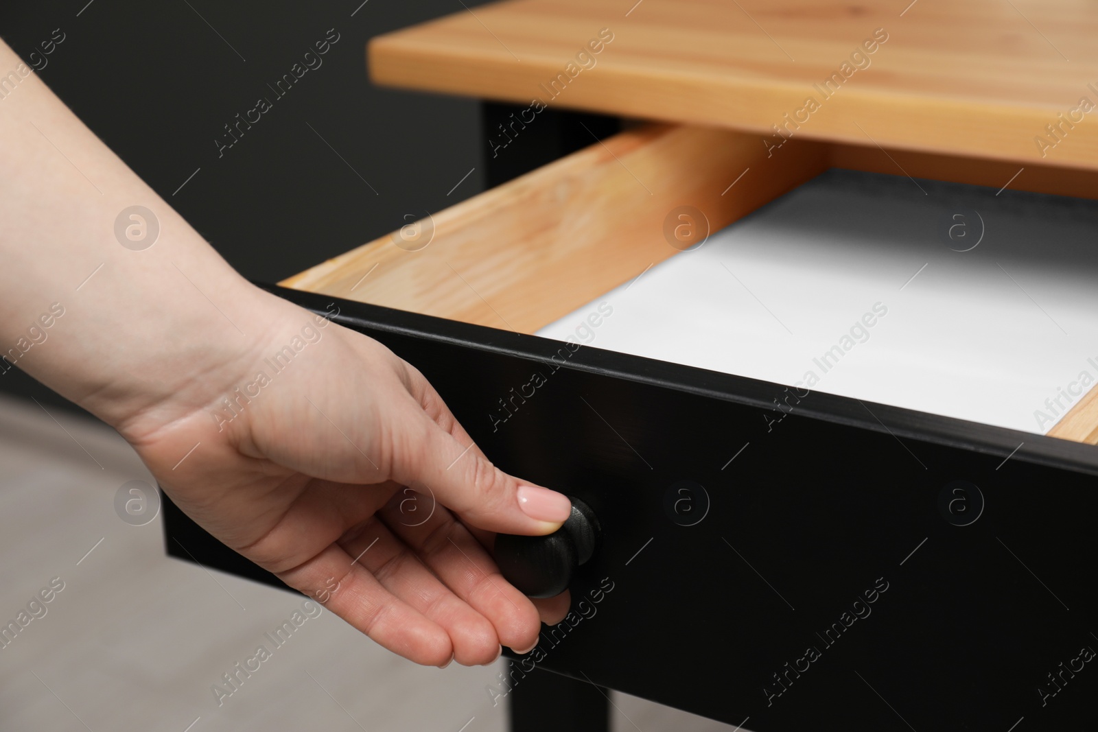 Photo of Woman opening empty desk drawer indoors, closeup view
