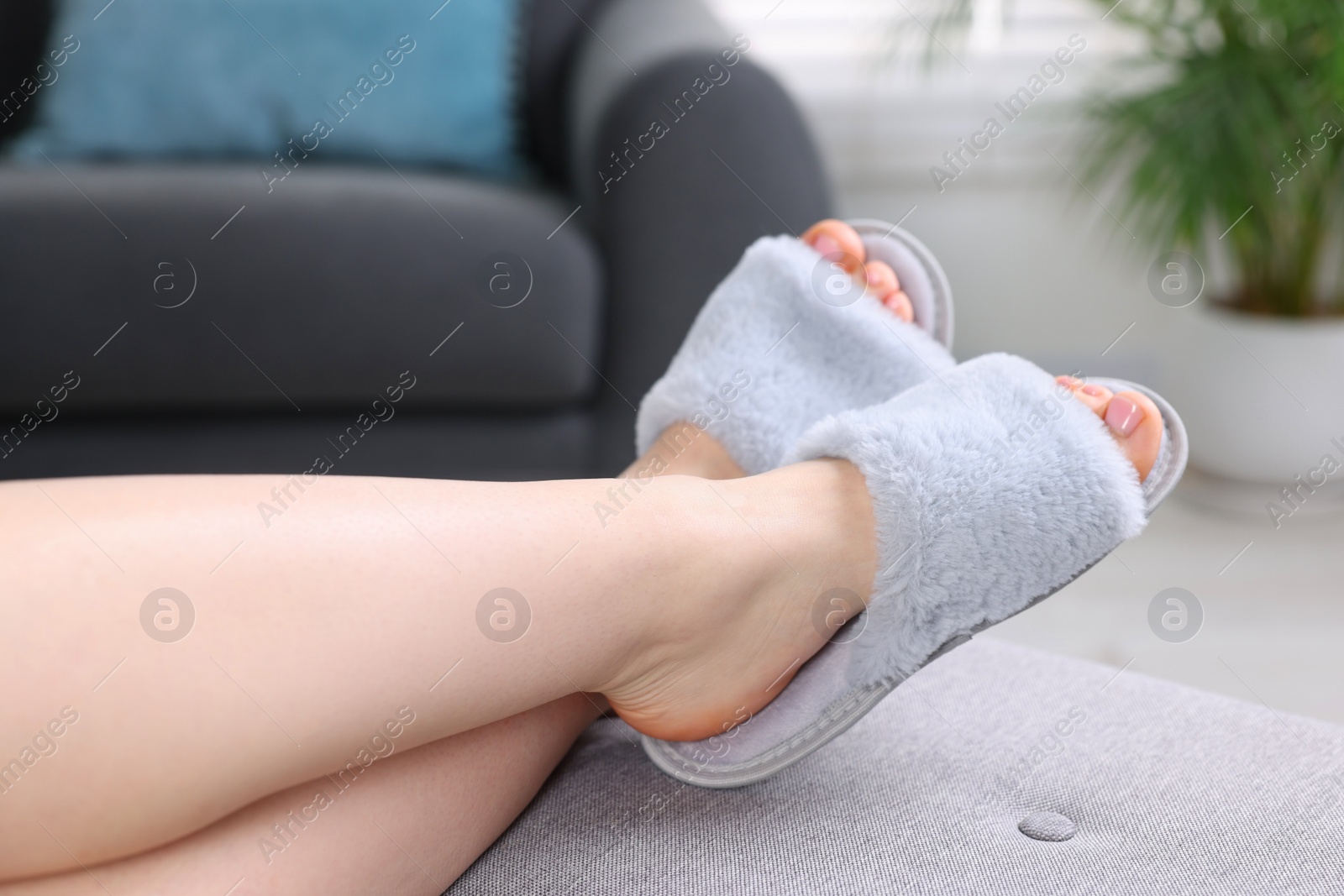 Photo of Woman in grey soft slippers resting at home, closeup