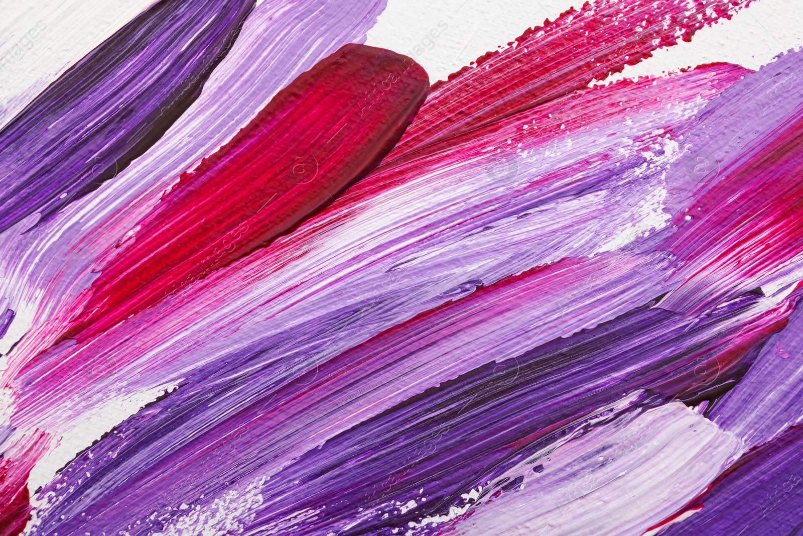 Photo of Beautiful strokes of bright oil paints on white canvas as background, closeup