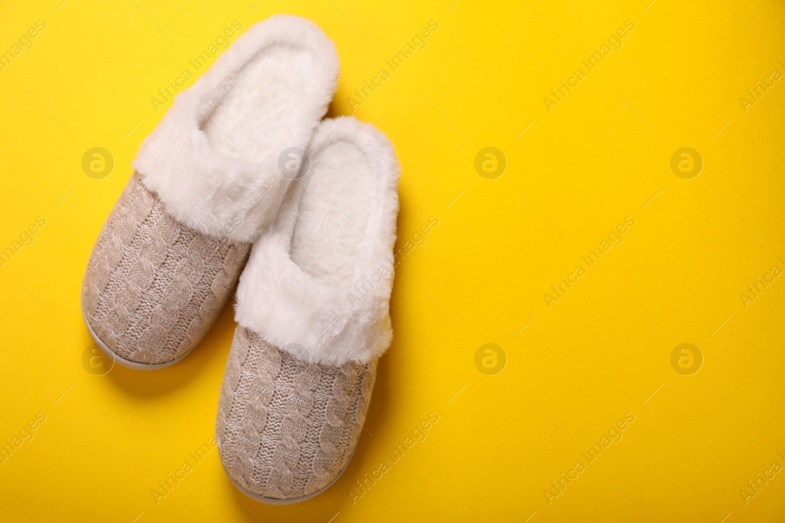 Photo of Pair of beautiful soft slippers on yellow background, top view