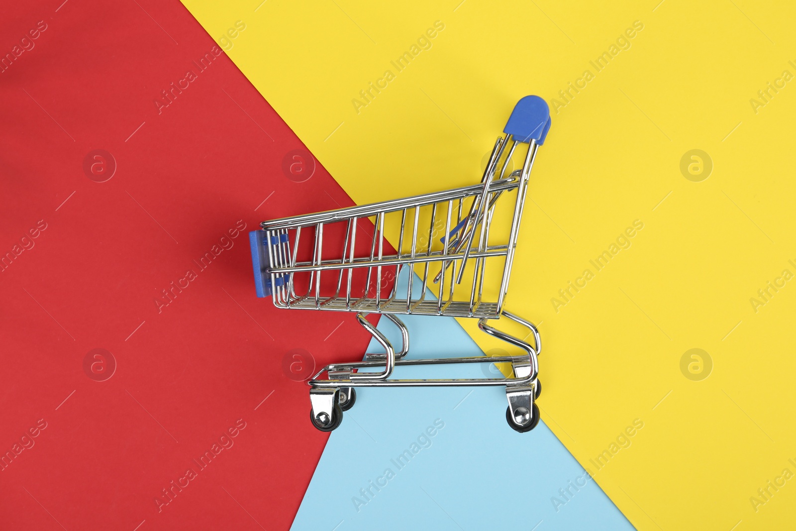 Photo of Empty shopping trolley on color background, top view