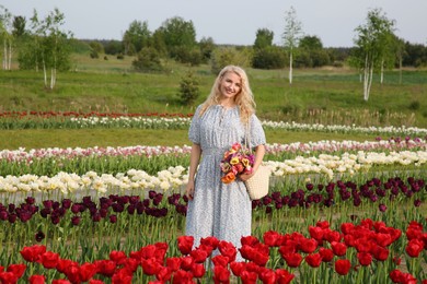 Photo of Woman with bag of spring flowers in beautiful tulip field