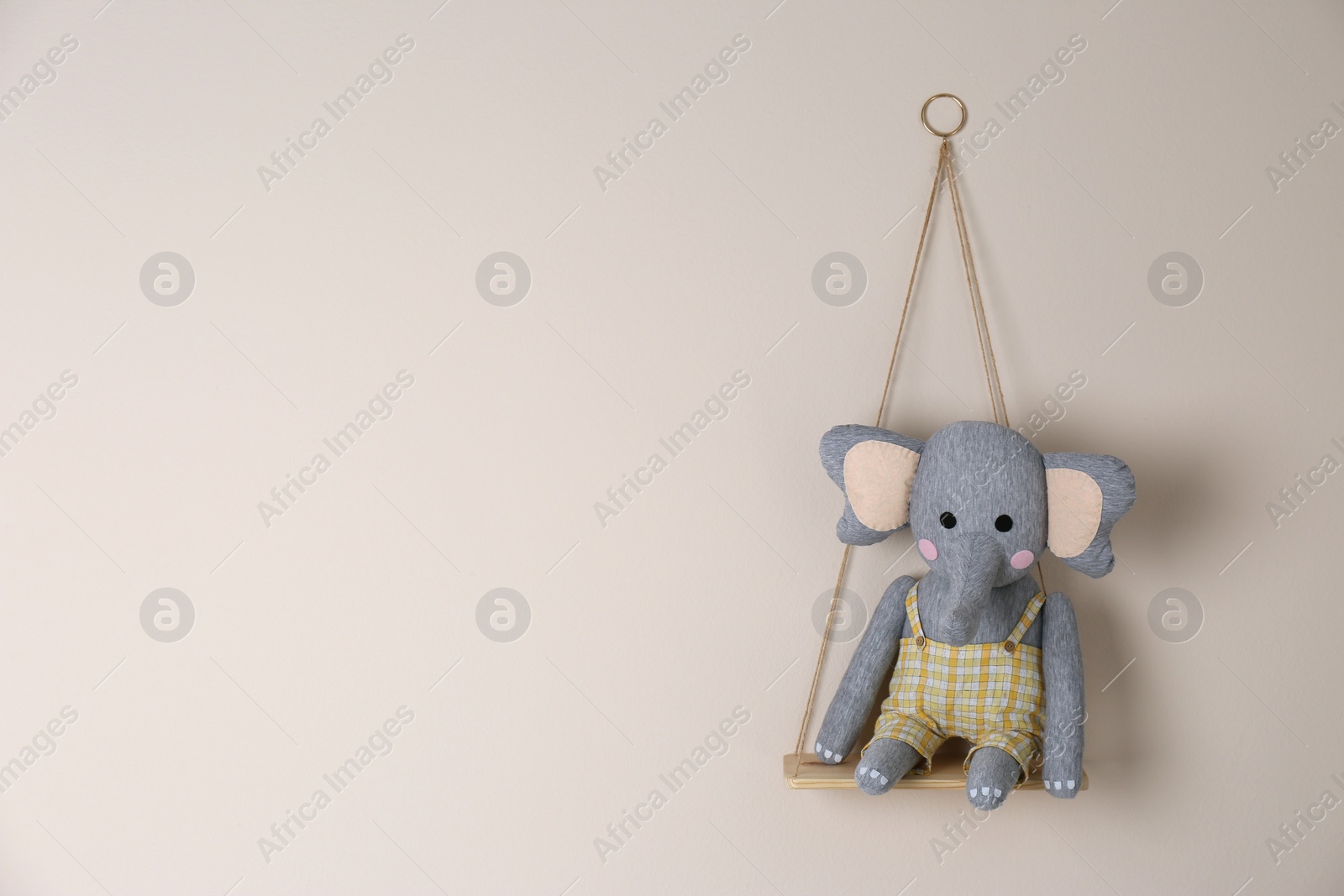 Photo of Shelf with cute toy elephant on beige wall, space for text. Child's room interior element