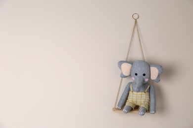 Photo of Shelf with cute toy elephant on beige wall, space for text. Child's room interior element