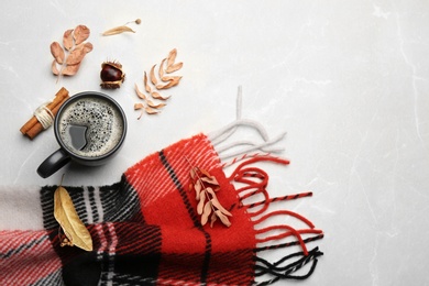 Flat lay composition with hot drink and warm plaid on light marble table, space for text