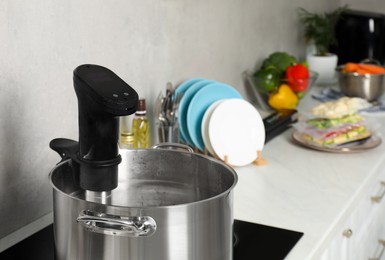 Photo of Pot with sous vide cooker in kitchen. Thermal immersion circulator