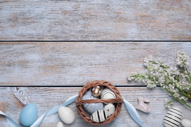 Flat lay composition with Easter eggs in basket on rustic wooden table. Space for text