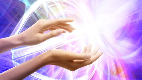 Image of Aura phenomena. Woman with flows of energy around her hands against color background, closeup
