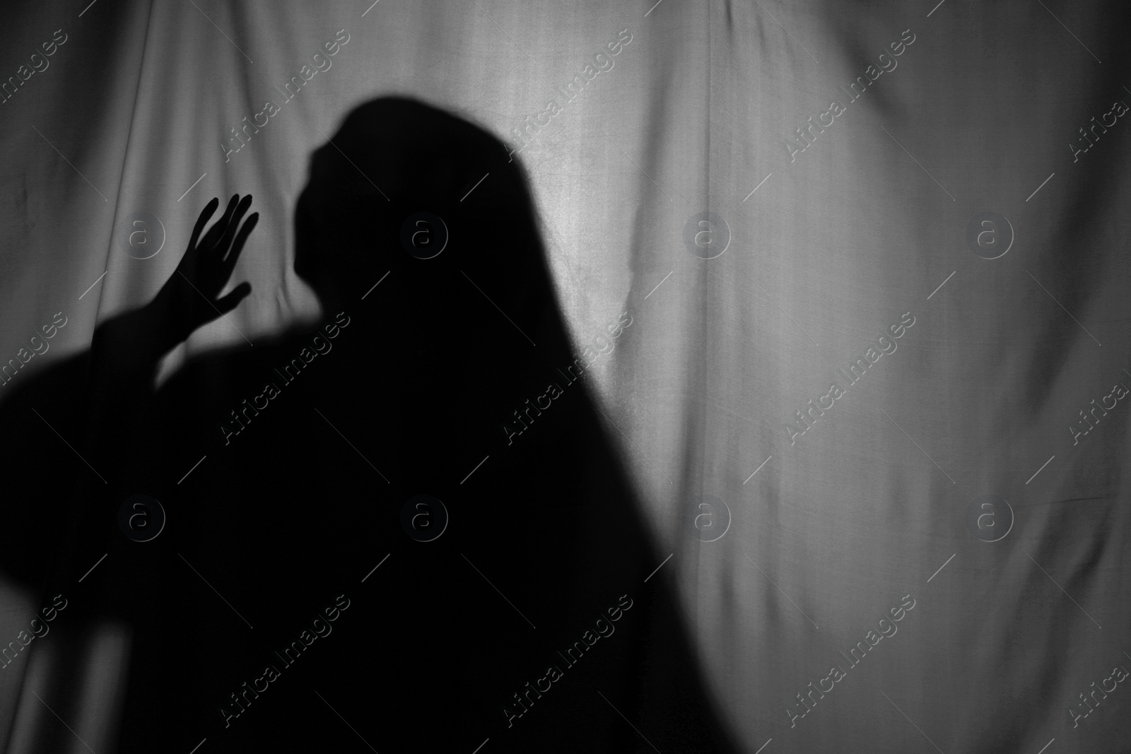 Photo of Silhouette of creepy ghost behind grey cloth, space for text