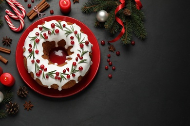 Photo of Flat lay composition with traditional Christmas cake and decorations on dark grey table, space for text