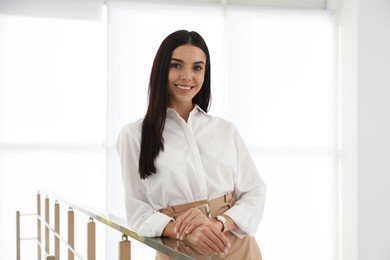 Photo of Happy young businesswoman leaning on railing in office