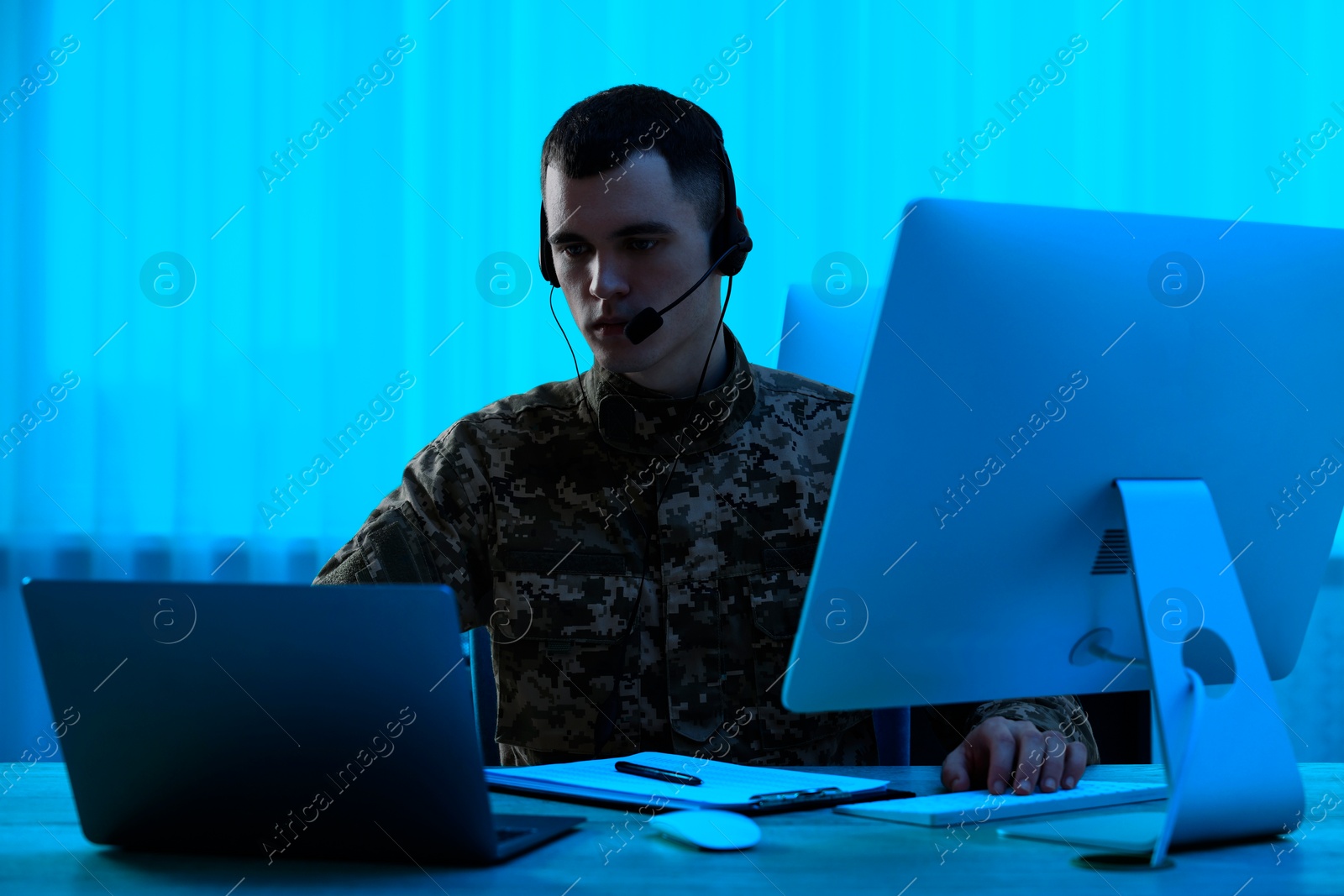 Image of Military service. Soldier in headphones working at table in office at night