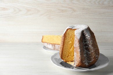 Delicious Pandoro cake decorated with powdered sugar on white wooden table, space for text. Traditional Italian pastry