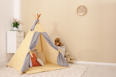 Photo of Cozy kids room interior with play tent and toys. Space for text