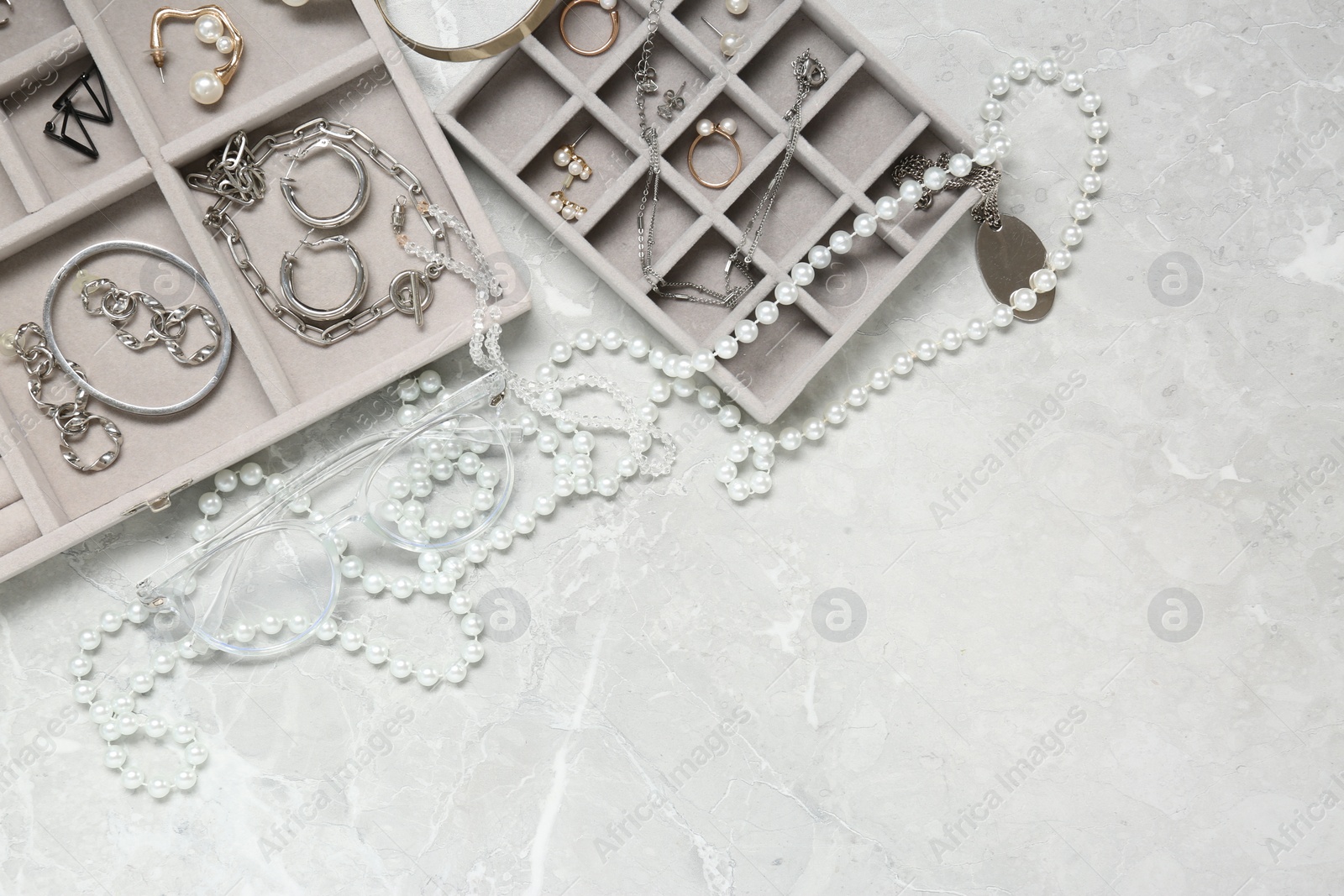 Photo of Jewelry boxes with many different accessories on light grey table, flat lay. Space for text