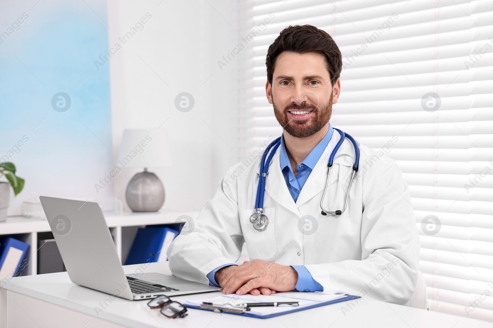 Photo of Medical consultant with stethoscope at table in clinic