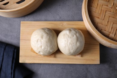 Delicious Chinese steamed buns on grey textured table, flat lay