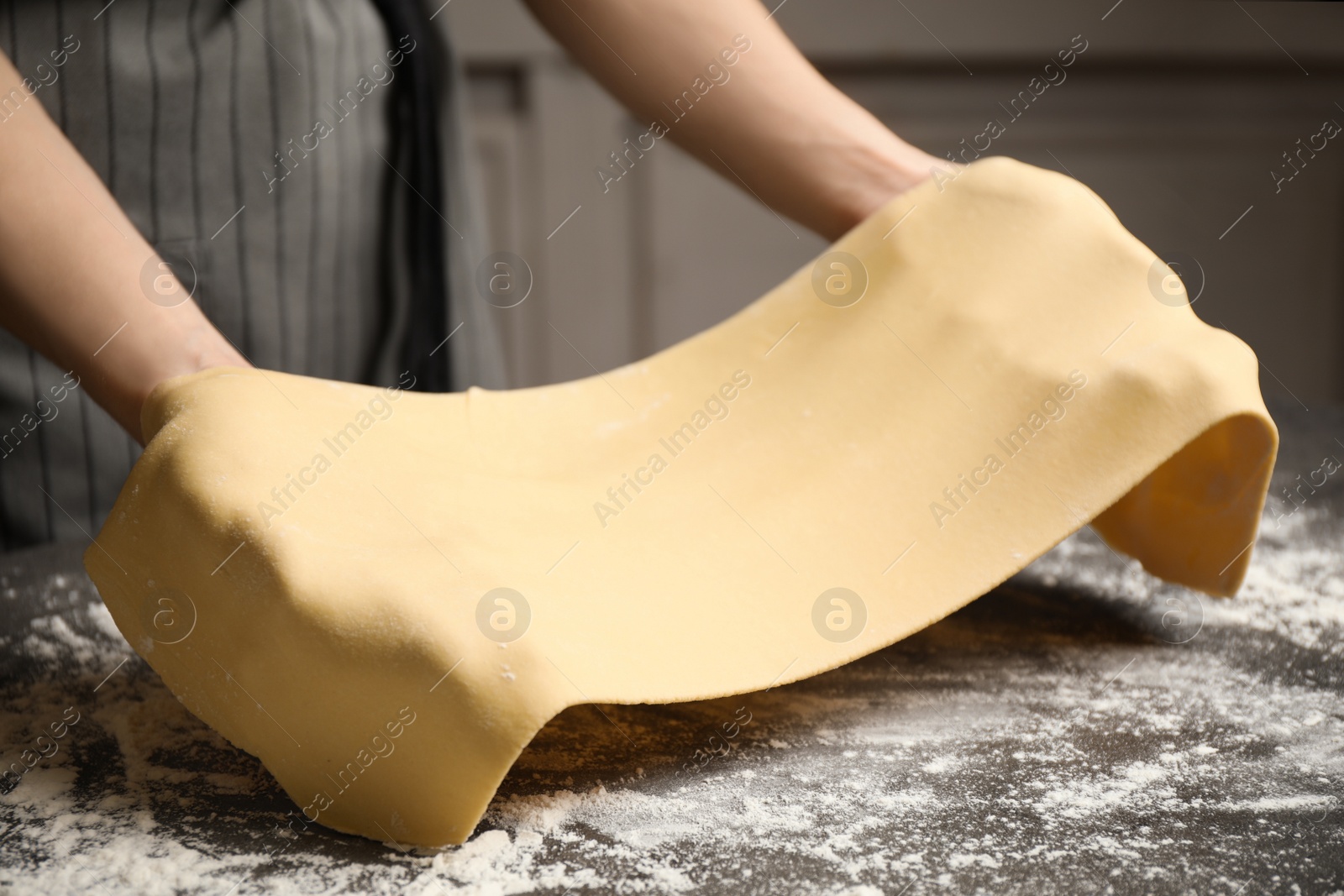 Photo of Woman with dough at grey table, closeup. Making pasta