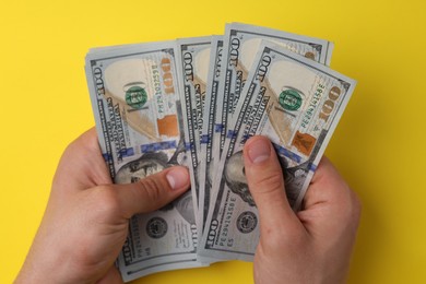 Money exchange. Man holding dollar banknotes on yellow background, top view