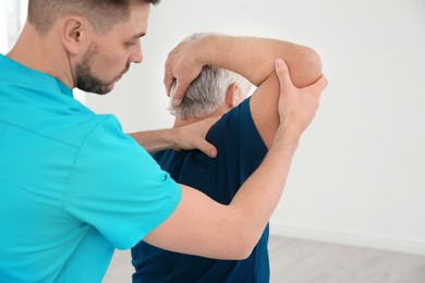 Young physiotherapist working with senior patient in clinic