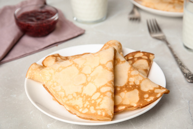 Photo of Folded fresh thin pancakes on light grey table