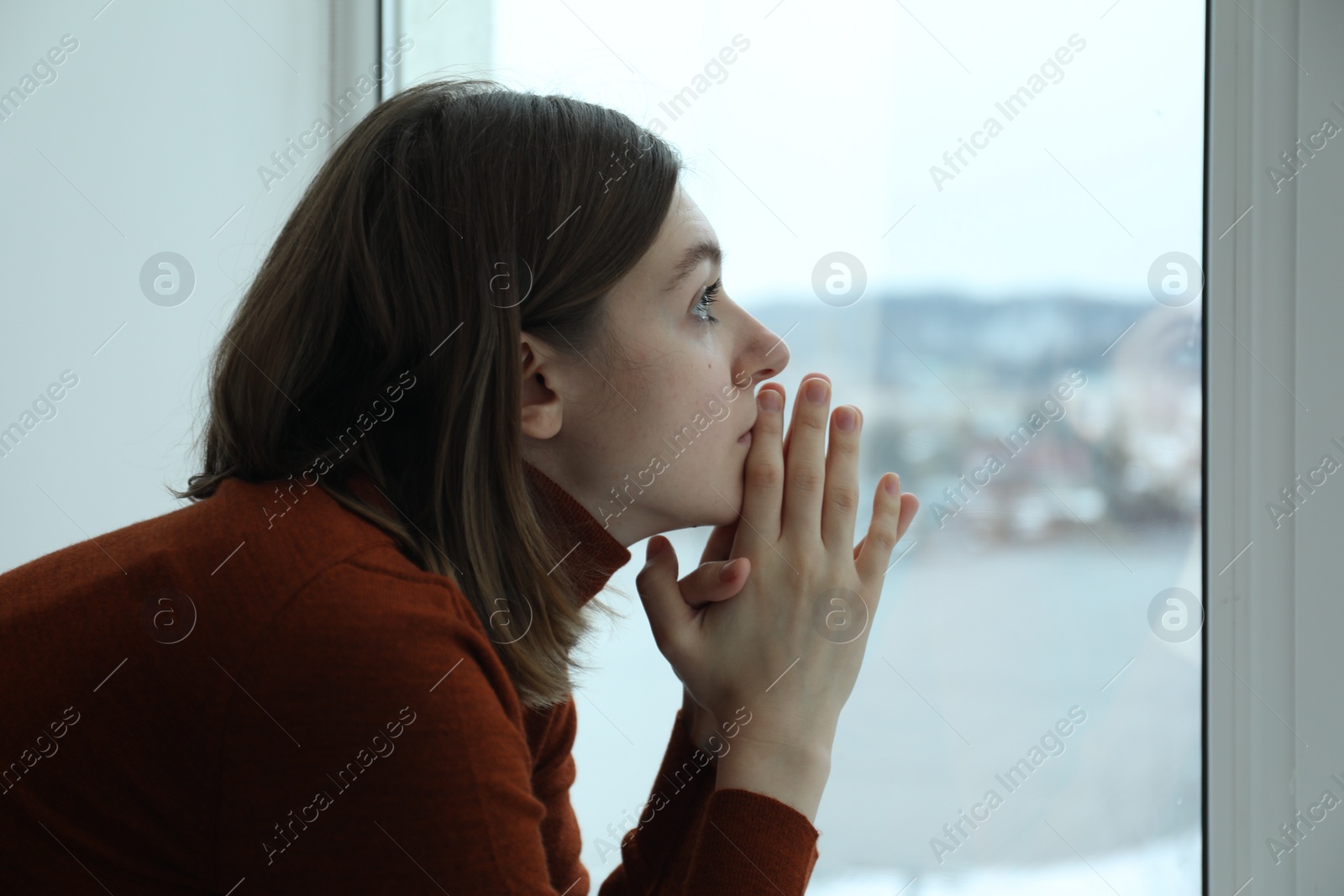 Photo of Sad young woman near window at home