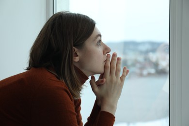 Photo of Sad young woman near window at home