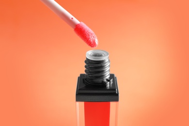 Photo of Applicator above liquid lipstick tube on color background