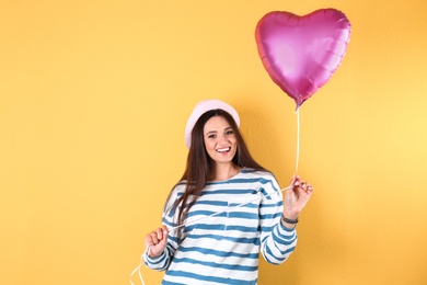 Photo of Portrait of young woman with heart shaped balloon on color background