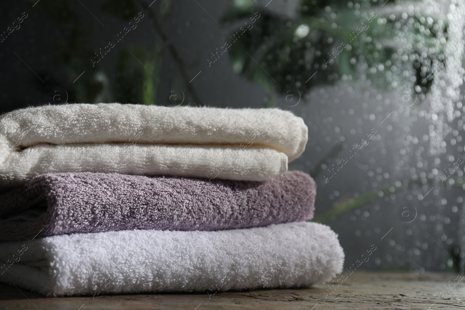Photo of Stacked terry towels on table in bathroom, space for text