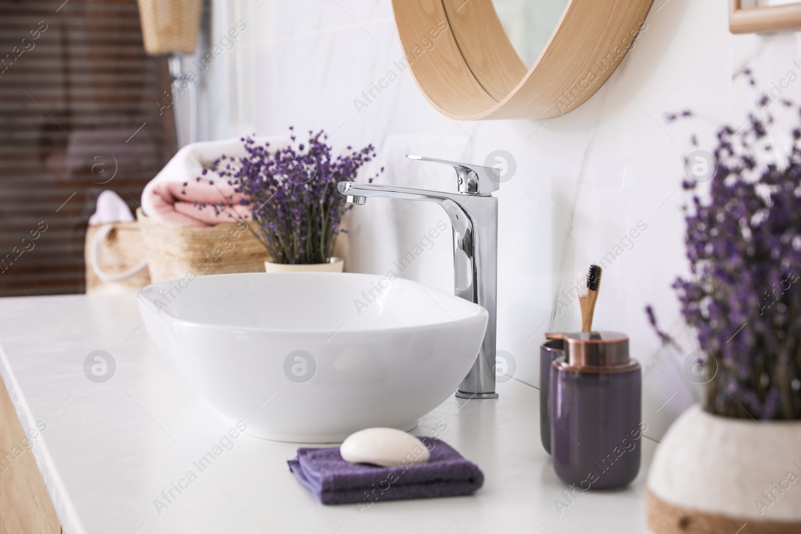 Photo of Bathroom counter with vessel sink, accessories and flowers. Interior design