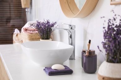 Bathroom counter with vessel sink, accessories and flowers. Interior design