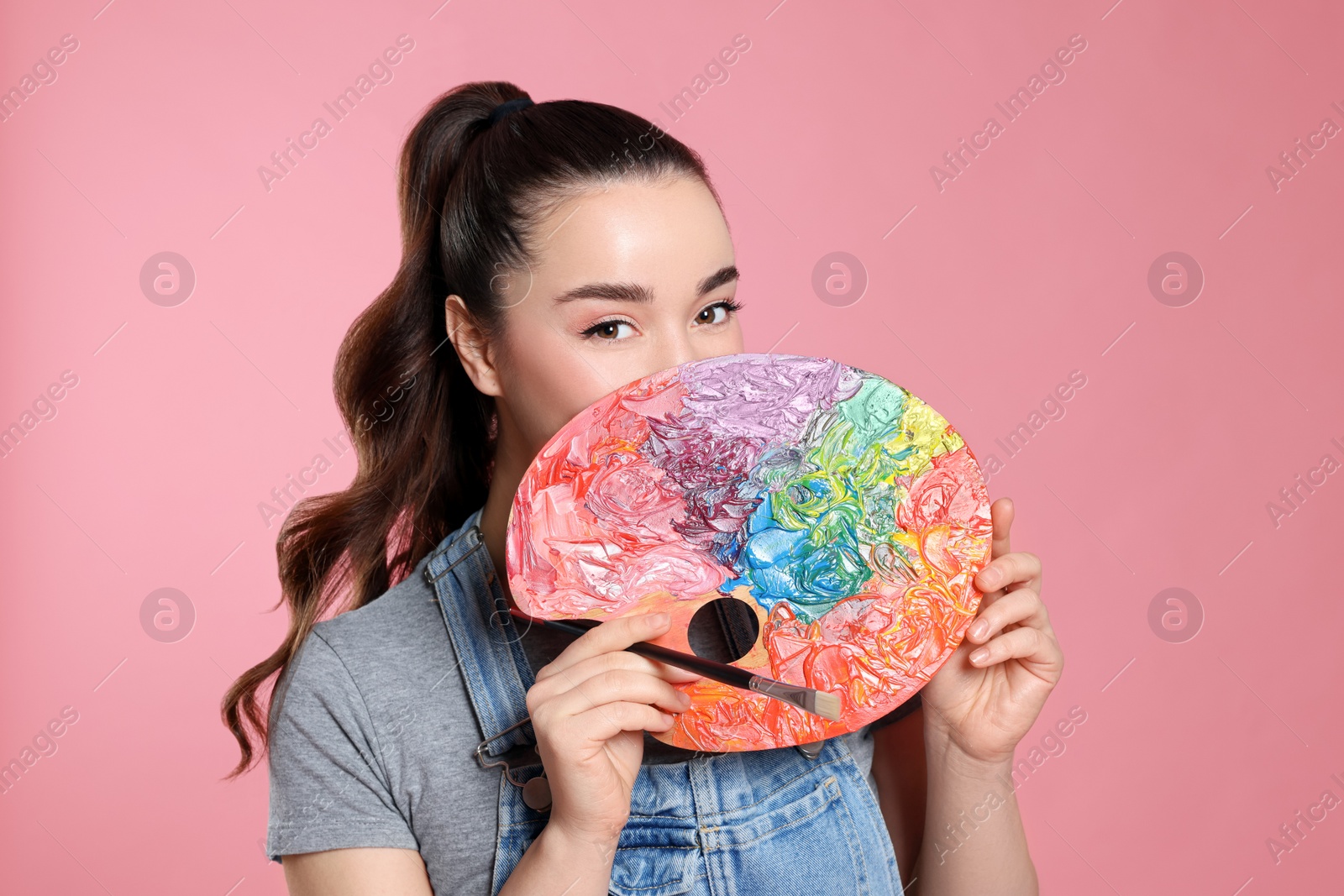 Photo of Woman with painting tools on pink background. Young artist