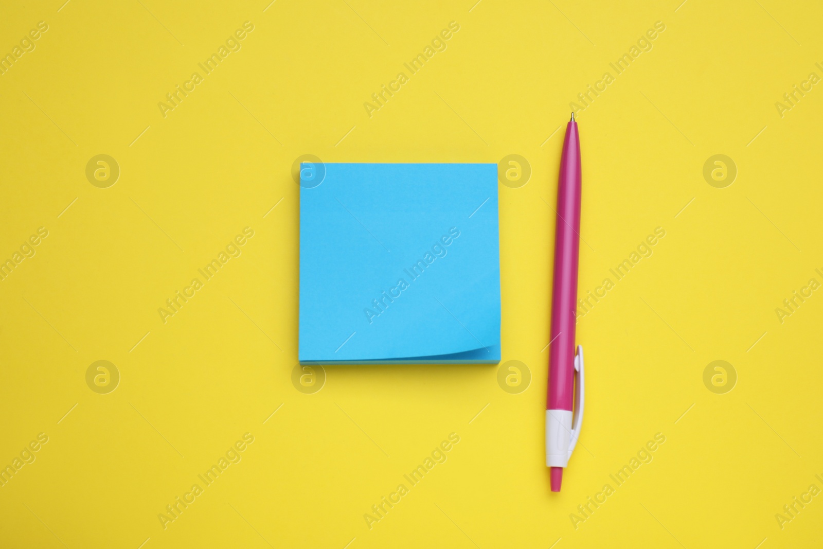 Photo of Paper note and pen on yellow background, flat lay