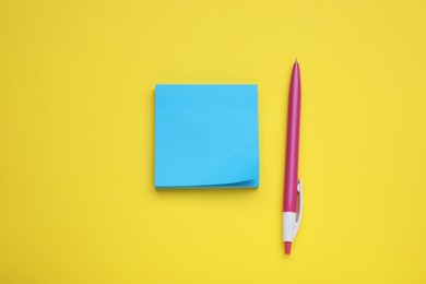 Photo of Paper note and pen on yellow background, flat lay