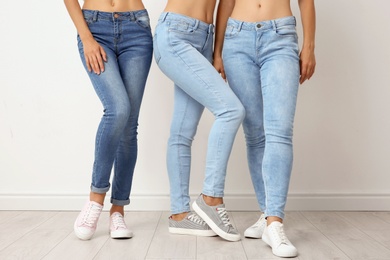 Photo of Group of young women in jeans near light wall