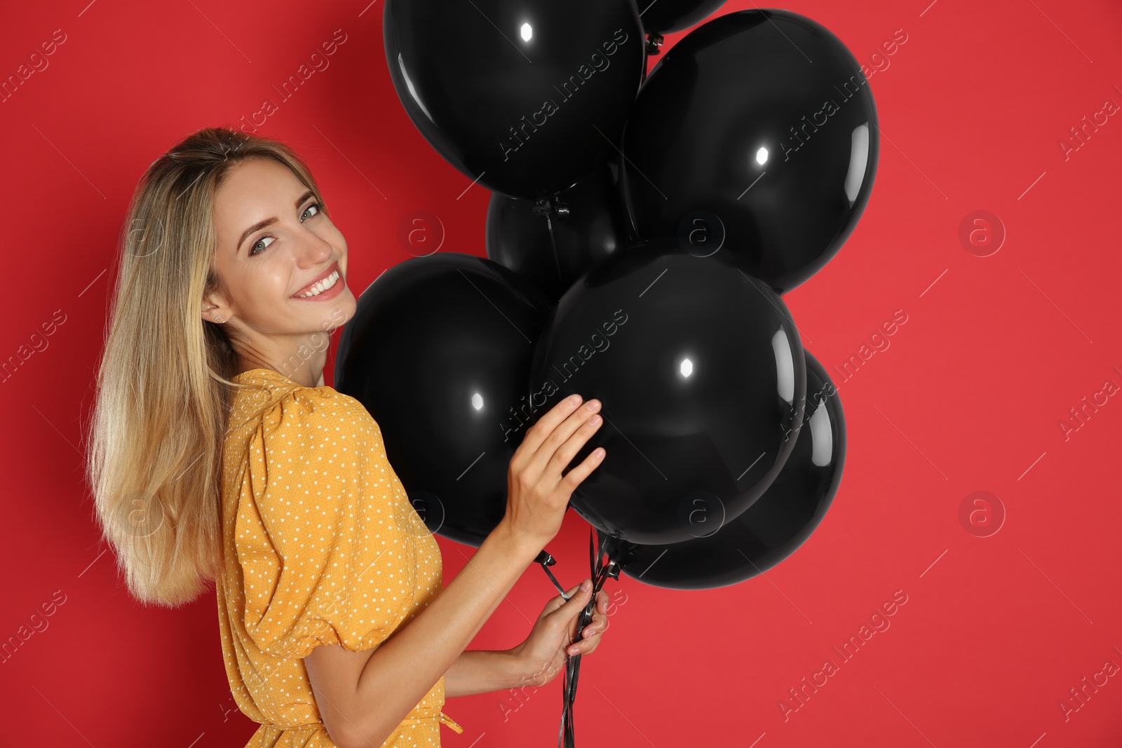 Photo of Happy young woman with balloons on red background. Black Friday Sale