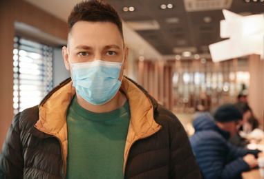Photo of Man with disposable mask in cafe. Virus protection