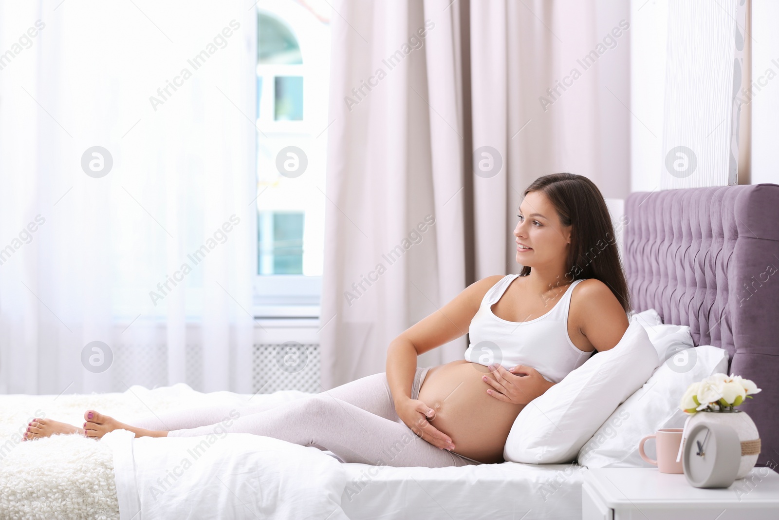 Photo of Happy pregnant woman lying on bed at home