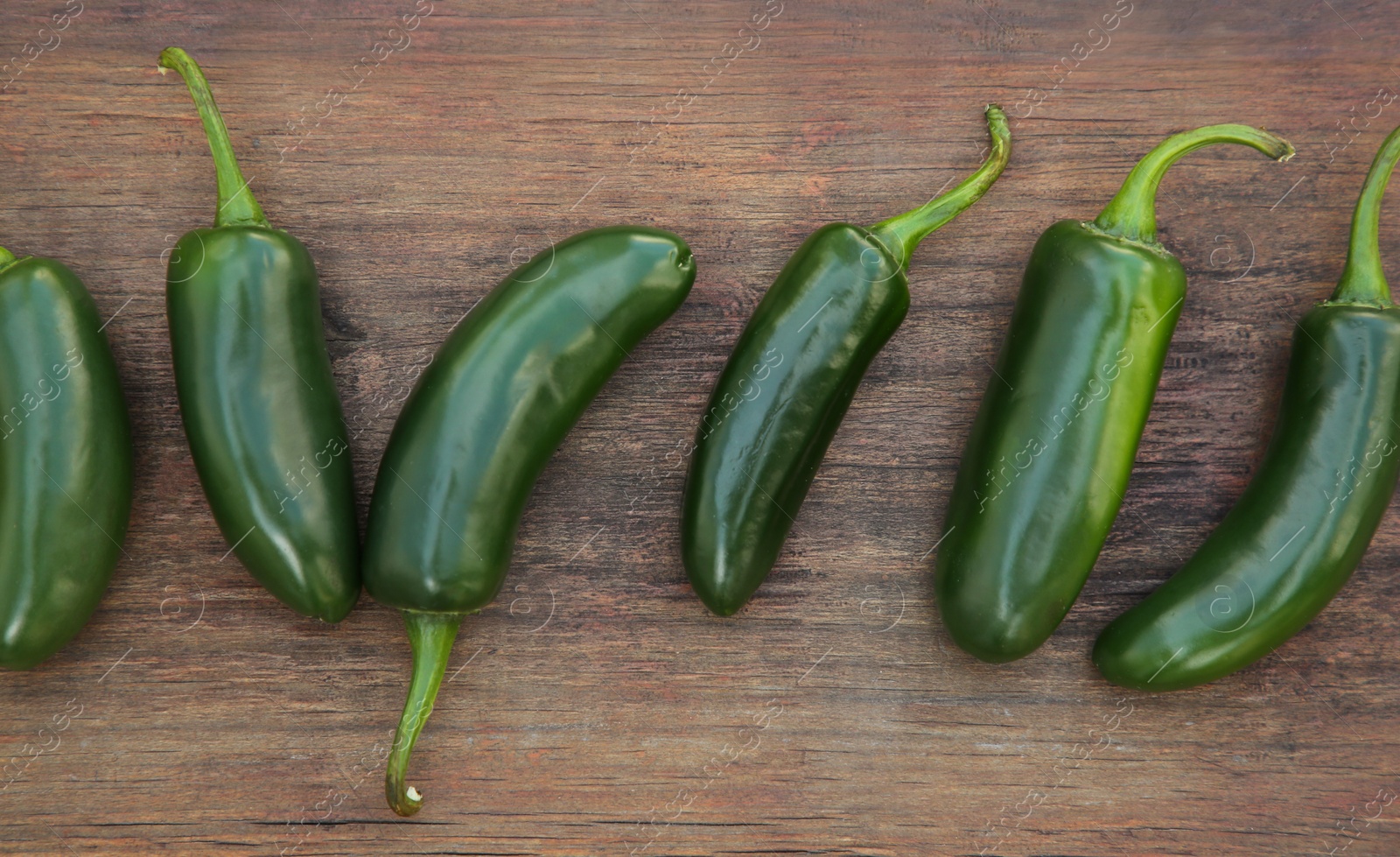 Photo of Fresh green jalapeno peppers on wooden table, flat lay