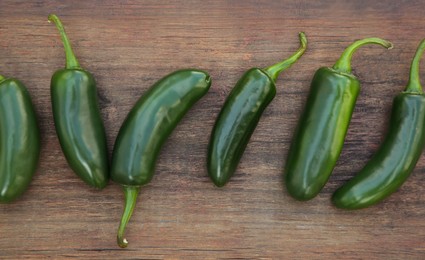 Fresh green jalapeno peppers on wooden table, flat lay