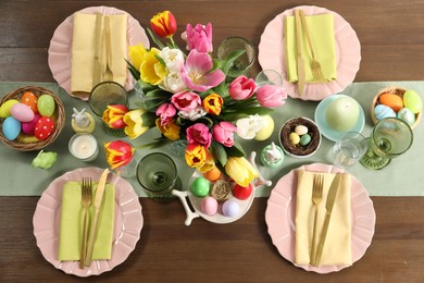 Photo of Easter celebration. Festive table setting with beautiful flowers and painted eggs, flat lay