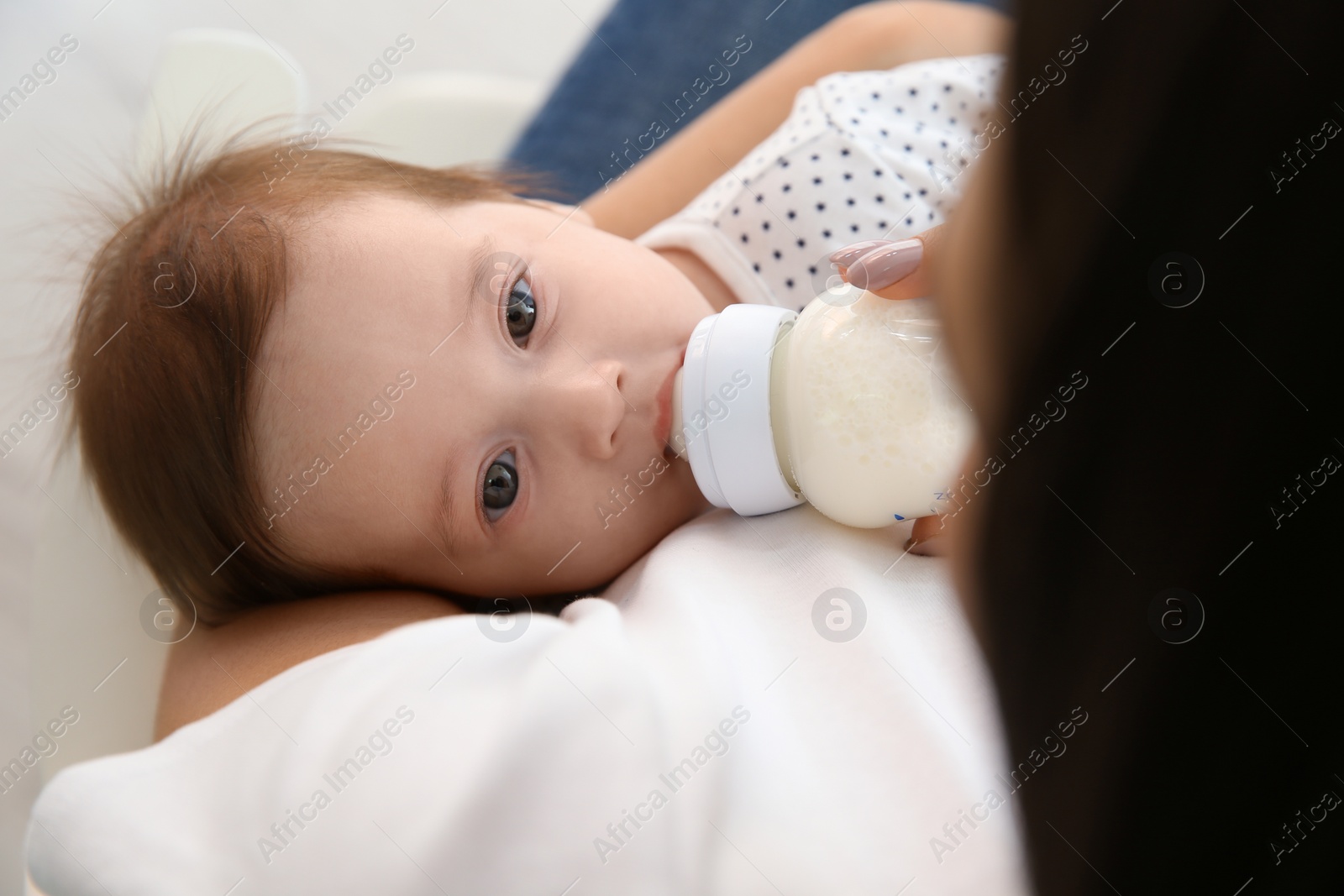 Photo of Woman feeding her baby from bottle at home, closeup