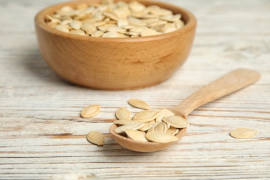 Photo of Raw unpeeled pumpkin seeds on white wooden table, closeup