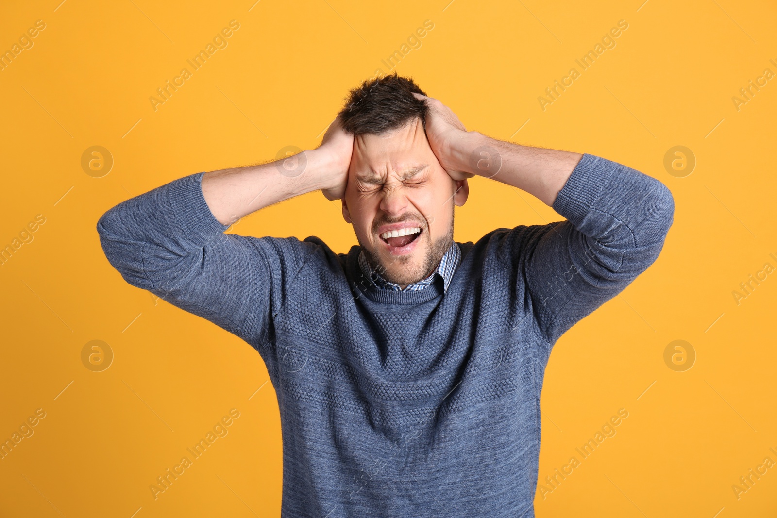 Photo of Man suffering from terrible migraine on yellow background