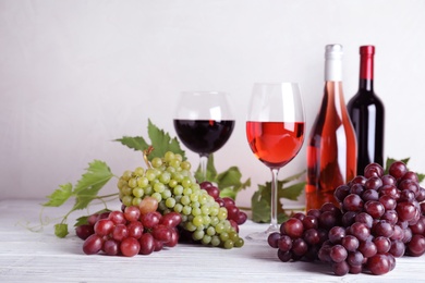 Photo of Fresh ripe juicy grapes and wine on white wooden table