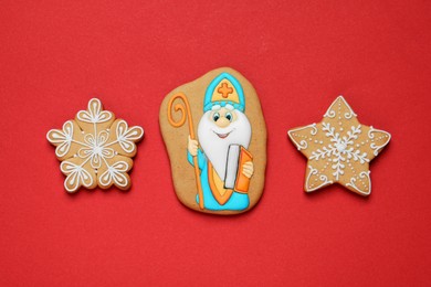 Tasty gingerbread cookies on red background, flat lay. St. Nicholas Day celebration