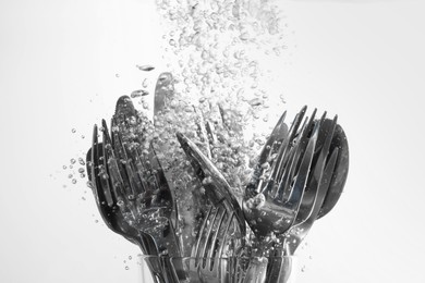 Washing silver cutlery in water on white background